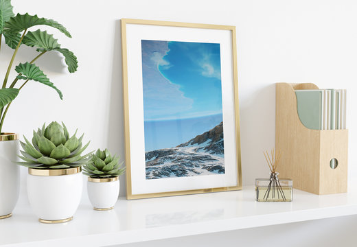 Golden frame leaning on white shelve in interior with plants and books mockup 3D rendering