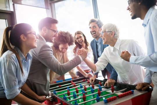 Employees playing table soccer indoor game in the office during break time