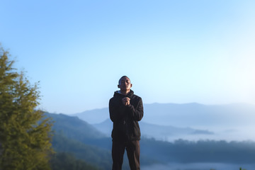 Man praying to God at morning on mountains with nature landscape. Christian concept.