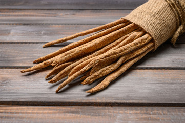 Italian traditional rye bread grissini on linen bag on wooden background. Close up