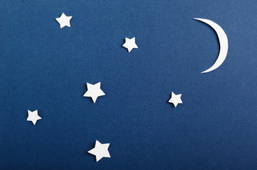 Moon and stars on blue background top view. Night sky objects with shadow close up. Decorative backdrop. Childish applique, homemade postcard. Starry heaven. Kid bedtime, nighttime concept.