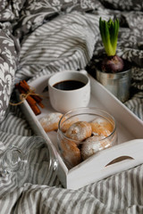 A beautiful white wooden tray with coffee, cookies and cream in a jug, on a gray background. breakfast concept in bed.