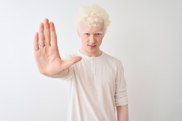 Young albino blond man wearing casual t-shirt standing over isolated white background doing stop sing with palm of the hand. Warning expression with negative and serious gesture on the face.