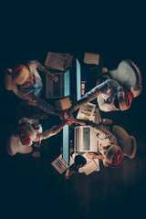 Vertical top above high angle view of four people coworking shaking hands spending Eve Noel...