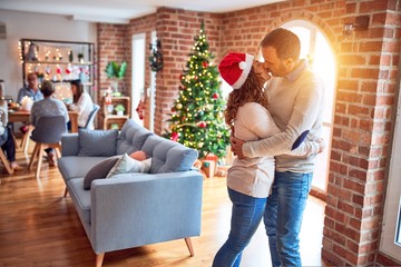 Family and friends dining at home celebrating christmas eve with traditional food and decoration, romantic senior couple hugging in love