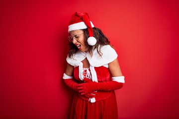 Middle age beautiful woman wearing Santa Claus costume over isolated red background with hand on stomach because nausea, painful disease feeling unwell. Ache concept.