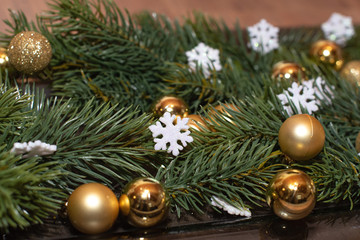 Obraz na płótnie Canvas Weihnachtsdekoration mit Tannenzweigen, goldenen Mini Christbaumkugeln, weißen glitzernden Schneeflocken Nahaufnahme Close Up Detailaufnahme