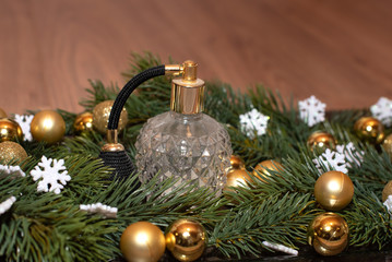 Vintage Parfumflakon mit Zerstäuber weihnachtlich dekoriert mit Tannenzweigen, goldenen Mini Christbaumkugeln, weißen glitzernden Schneeflocken Close up Detailaufnahme