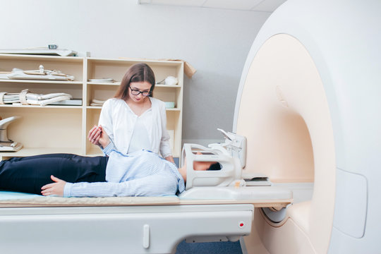 Radiologic model technician smiling help at mature female patient lying on a CT Scan bed