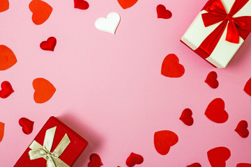 Valentine s day flatly copy space.  On a pink background is a gift box and a red bow, red paper hearts, hearts made of white fabric and red satin. In the center is a place for text.