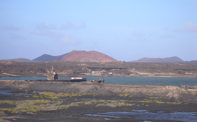 salt lake with industrial buildings in front of volcanic mountains