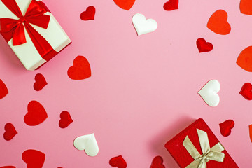 Valentine s day flatly copy space.  On a pink background is a gift box and a red bow, red paper hearts, hearts made of white fabric and red satin. In the center is a place for text.