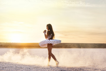 Tender young ballerina dancer in a snow-white tutu dress and white pointe shoes on a salty dried lake. Fantastic landscape and a girl  ballerina © Ann Stryzhekin