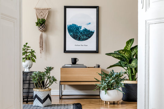 Modern scandinavian living room interior with black mock up poster frame, design commode, a lot of plants in different pots, macrame and elegant accessories. Template. Stylish home decor. 