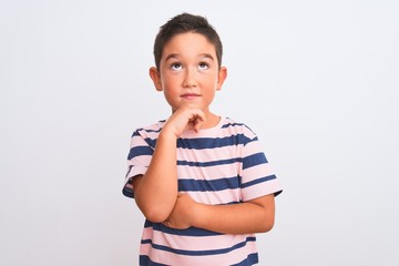 Beautiful kid boy wearing casual striped t-shirt standing over isolated white background with hand on chin thinking about question, pensive expression. Smiling with thoughtful face. Doubt concept.