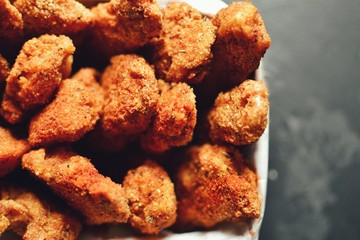 Chicken nuggets on a dark background. Grilled fish and meat in batter. Fish sticks. Meat sticks. Nuggets with tomato and parsley in a basket. Place for your text.