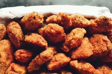 Chicken nuggets on a dark background. Grilled fish and meat in batter. Fish sticks. Meat sticks. Nuggets with tomato and parsley in a basket. Place for your text.