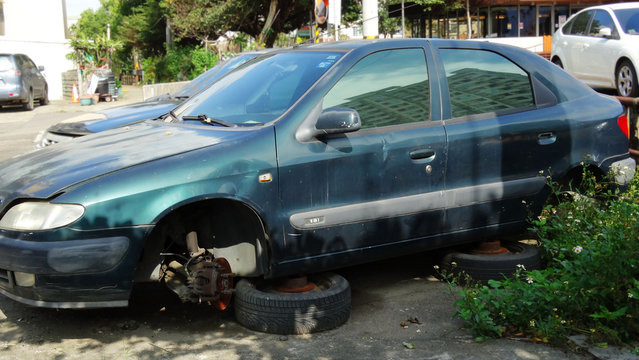 Scrapped broken car in outdoor. Rusty abandoned car with no tire in outdoor.