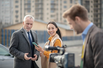 Young cute female reporter smiling to a videocamera
