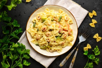 Italian pasta in a creamy sauce with shrimp on a plate, top view. Pasta in the form of bows on a dark table background. 