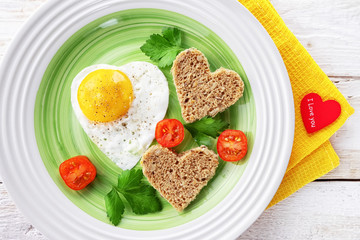 Tomatoes, fried egg and bread in the shape of a heart. Romantic food Valentine day Breakfast with a red heart and the text I love you.