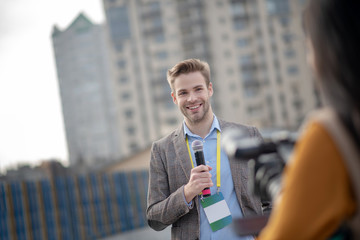 Young bearded reporter holding a microphone in his hand