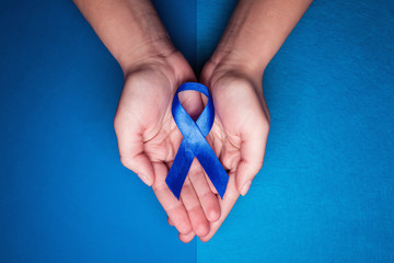 blue ribbon in support of trafficking and sexual slavery. Blue ribbon on female hands on a blue...