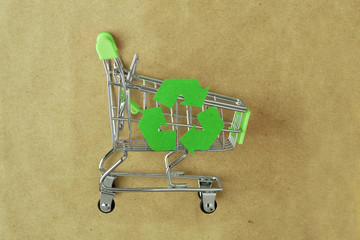 Green shopping cart with recycle symbol on recylced paper - Concept of ecology and responsible shopping