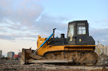 Track-type bulldozer, earth-moving equipment. Land clearing, grading, pool excavation, utility trenching, utility trenching and foundation digging during of large construction jobs.