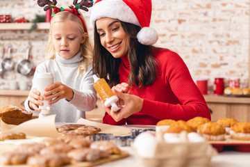 Happy mother and daughter decorating Christmas cookies