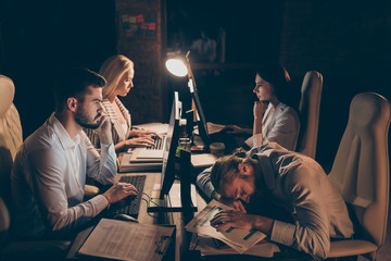 Profile side view of nice attractive focused concentrated coworkers gathering meeting completing task urgent report researching data at night preparing report at work place station dark room