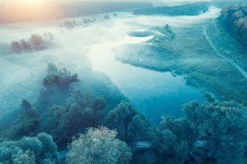 Fototapeta na wymiar Early misty morning in the countryside. Sunrise over the river. Rural landscape in summer. Aerial view