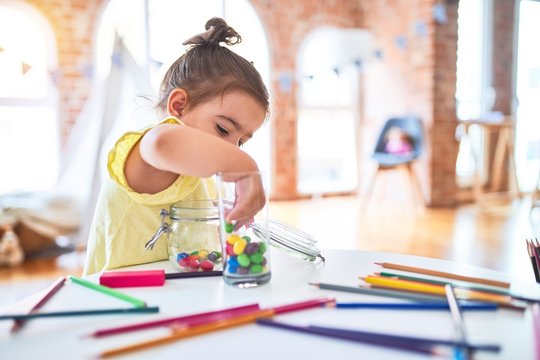 Beautiful toddler standing playing with chocolate colored balls on the table at kindergarten
