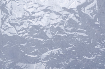 Rumpled plastic wrapping material on the grey surface as a background