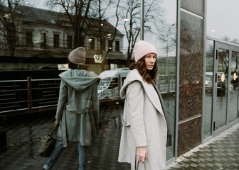 Young brunette woman walking around the city. She's wearing a gray coat and blue jeans