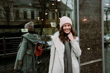 Young brunette woman walking around the city. She's wearing a gray coat and blue jeans
