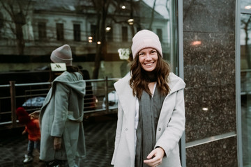 Young brunette woman walking around the city. She's wearing a gray coat and blue jeans