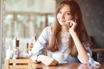 Young business woman talking on the phone in coffee shop