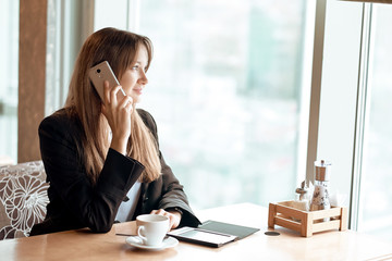 Young business woman talking on the phone in coffee shop