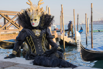 Fototapeta na wymiar Female mask at the Venice carnival wearing a black and gold dress