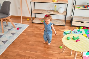 Beautiful caucasian infant playing with toys at colorful playroom. Happy and playful at kindergarten.