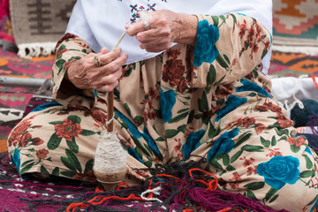 Antique spinning wheel in the hands of an old woman