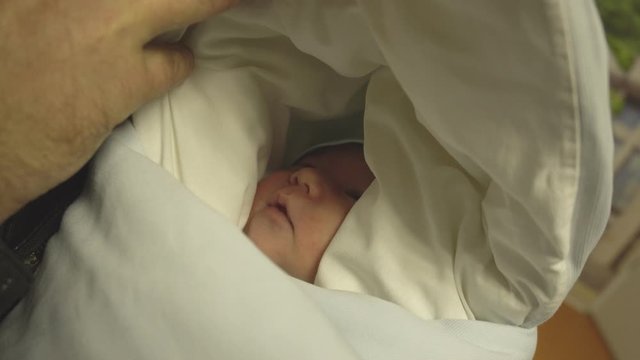 Father takes a newborn beautiful baby from the hospital home, close-up