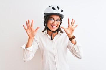 Beautiful businesswoman wearing glasses and bike helmet over isolated white background showing and pointing up with fingers number ten while smiling confident and happy.