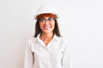 Young beautiful architect woman wearing helmet and glasses over isolated white background with a happy and cool smile on face. Lucky person.
