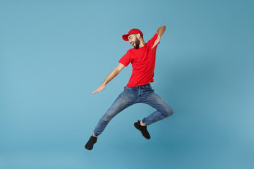 Delivery man in red uniform workwear isolated on blue wall background, studio portrait. Professional male employee in cap t-shirt print working as courier dealer. Service concept. Mock up copy space.