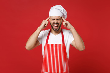 Frustrated male chef cook or baker man in striped apron toque chefs hat posing isolated on red...