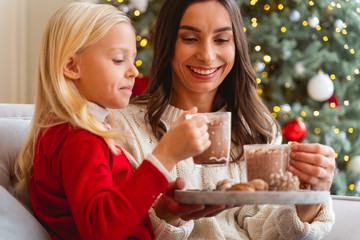 Smiling woman looking at her daughters drink
