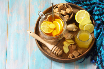 Cup of hot tea with lemon, ginger, honeycomb and honey on a wooden table. Copy space.