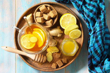 Cup of hot tea with lemon, ginger, honeycomb and honey on a wooden table. Top view on a flat background.